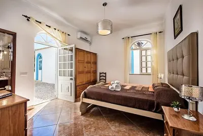 a bedroom with a bed and a table and a door at Villa Cabrita, Superb location, large villa, walk to restaurants, supermarkets beach in Guia