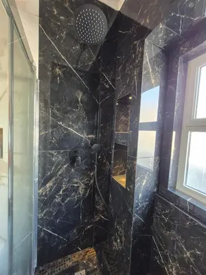 a bathroom with a shower with black marble at AL Barbinha in Faro