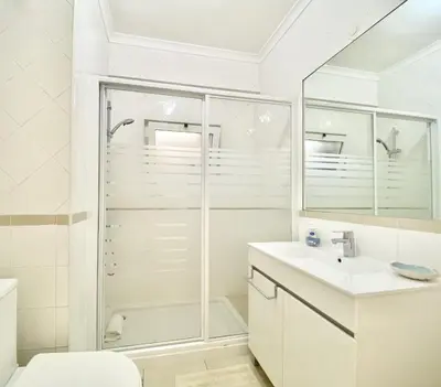 a white bathroom with a shower and a sink at Torre 20 - Near the beach - Quarteira in Quarteira