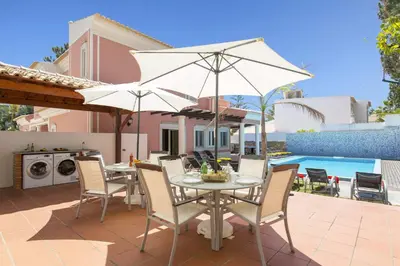a patio with a table and chairs and an umbrella at Villa Falesia Mar by Villa Plus in Olhos de Água