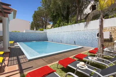 a swimming pool with lounge chairs next to a wall at Villa Falesia Mar by Villa Plus in Olhos de Água