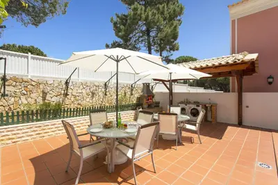 a patio with a table and chairs and an umbrella at Villa Falesia Mar by Villa Plus in Olhos de Água
