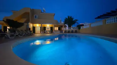 a house with a white fence and palm trees at Villa Rafaela com piscina Albufeira in Albufeira