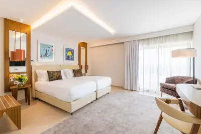 a hotel room with a bed and a chair at Regency Salgados Hotel & Spa in Albufeira