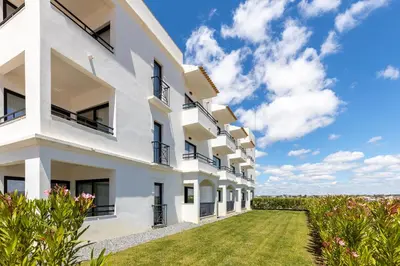 an exterior view of a white apartment building with a green yard at Regency Salgados Hotel & Spa in Albufeira