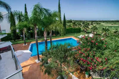 a swimming pool in a yard with palm trees and flowers at Villa Laguna, Golf - Stunning house - Laguna Golf Course in Quarteira