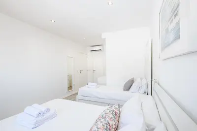 a white room with two beds and a mirror at Atlantic Breeze Apartments by Atlantic Places in Albufeira