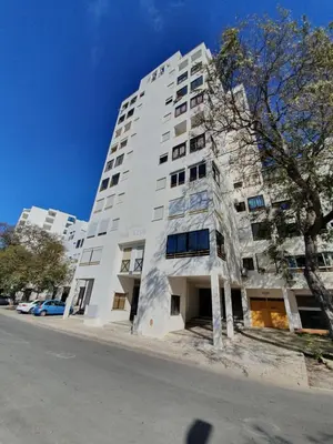 a tall white building on the side of a street at Apartamento Margarita in Quarteira