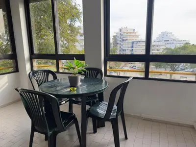 a table and chairs in a room with windows at Apartamento Margarita in Quarteira
