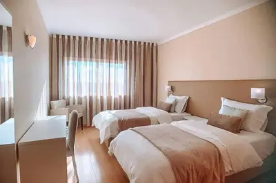 a hotel room with two beds and a window at Plant Paradise Apartment in Albufeira