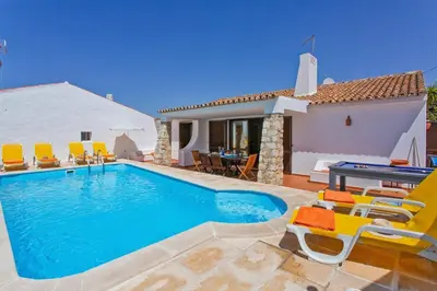 a swimming pool with chairs and a pool table at Villa Aveiros by Villa Plus in Albufeira