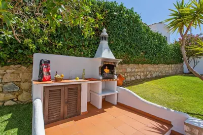 a outdoor kitchen with a fireplace in a yard at Villa Aveiros by Villa Plus in Albufeira