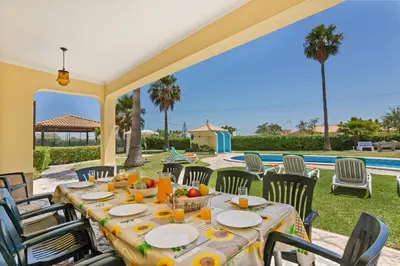 a table set for a meal on a patio with a pool at Villa Barreto by Villa Plus in Pêra