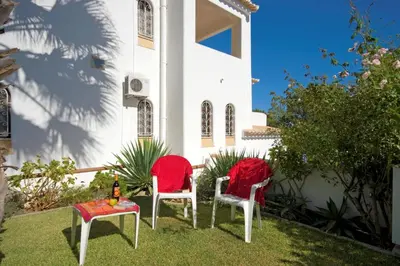 two red chairs and a table in front of a house at Villa Elanor by Villa Plus in Albufeira