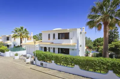 a white house with palm trees on a street at Villa Elanor by Villa Plus in Albufeira