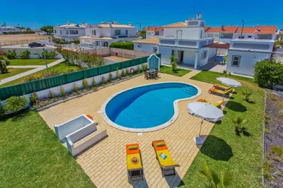 a swimming pool with lounge chairs and a house at Villa Gale Palm by Villa Plus in Albufeira