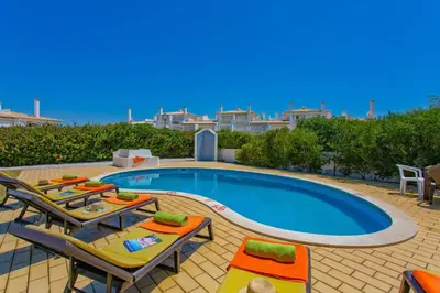 a swimming pool with tables and chairs next to a villa at Villa Hope by Villa Plus in Galé