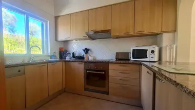 a kitchen with wooden cabinets and a microwave at Green and Blue View Apartment in Albufeira