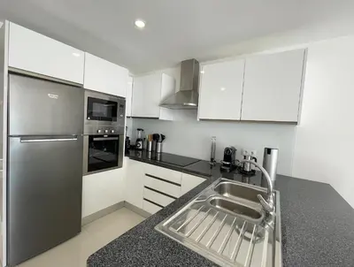 a kitchen with white cabinets and a stainless steel sink at Casa Rosa - Vilamoura in Vilamoura