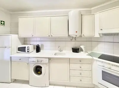 a white kitchen with a washing machine and a sink at Alcharb - Pool & City Center - Vilamoura in Quarteira