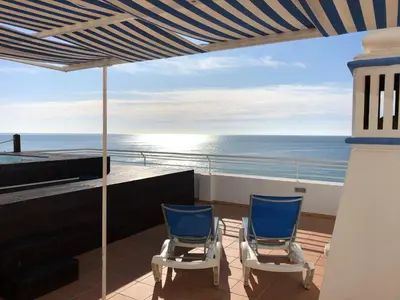two blue chairs on a balcony overlooking the ocean at Casa da Praia in Albufeira
