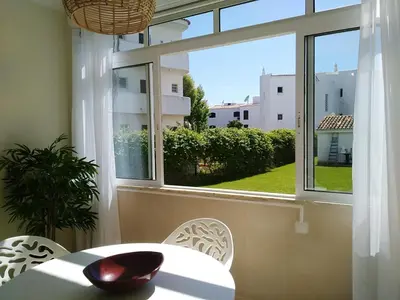 a table and chairs in a room with a window at Garden View Vilamoura Apartment in Vilamoura