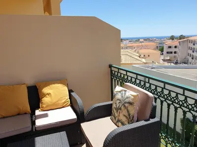 a balcony with a couch and pillows on a balcony at Oura Beach T1 apartment Coral , close to the Strip, Swimming Pool, Wi Fi, A/C in Albufeira