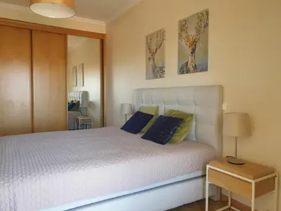 a bedroom with a white bed with blue pillows at Oura Beach T1 apartment Coral , close to the Strip, Swimming Pool, Wi Fi, A/C in Albufeira