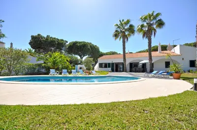 a swimming pool in front of a house with palm trees at Close to Beaches and All Amenities, Private Pool, Free AC and Wifi in Quarteira