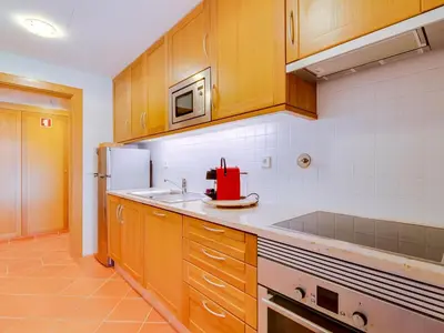 a kitchen with wooden cabinets and a red appliance at AL - Apartamento Vila Sol F5 AE in Vilamoura