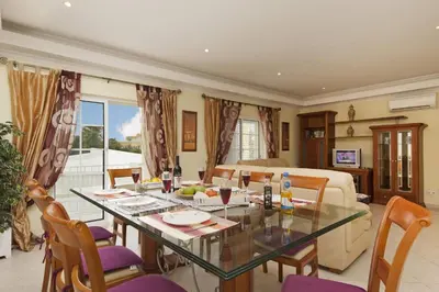 a dining room and living room with a table and chairs at Villa Cubos by Villa Plus in Albufeira