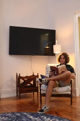 a woman sitting in a chair reading a book at 4 Cantos in Faro