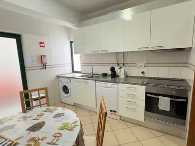 a kitchen with a refrigerator and a sink and a table at Apartamento Canaima in Quarteira