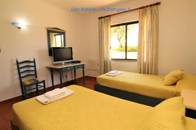 a room with two beds and a desk and a television at São Rafael - Hydrangea 5, Apt. T2 - Albufeira in Albufeira