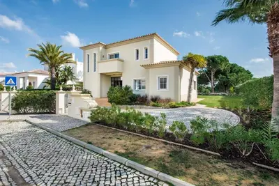 a large white house with palm trees and a driveway at Villa Palm Golfe, fantastic house on Vila Sol course, kids pool, aircon in Quarteira