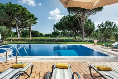 a swimming pool with two chairs and an umbrella at Villa Palm Golfe, fantastic house on Vila Sol course, kids pool, aircon in Quarteira