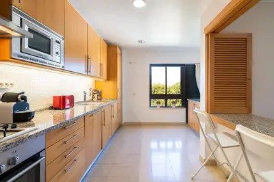 a kitchen with wooden cabinets and a microwave at Corcovada in Albufeira