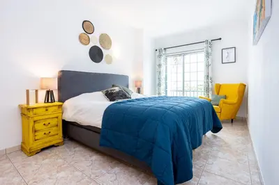 a bedroom with a bed and a yellow chair at Casa Primavera in Albufeira