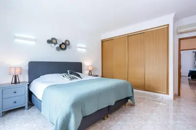 a bedroom with a large bed and a wooden cabinet at Casa Primavera in Albufeira