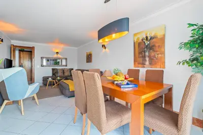 a dining room and living room with a wooden table and chairs at Duplex Sea View by Albufeira Holidays in Albufeira