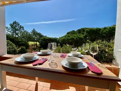 a wooden table with glasses and plates on top of it at Victory Village Quinta do Lago - Spacious 2 Bed / 3 Bath Apartment in Almancil