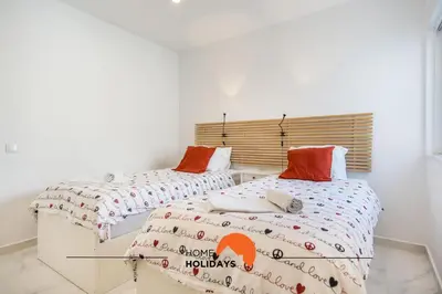 two beds in a white room with avertisement for at #052 V4 Mimosas by Home Holidays in Albufeira