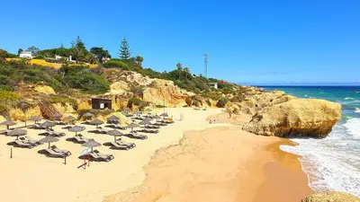 a beach with chairs and umbrellas and the ocean at Beach villa with ocean view and rooftop cinema in Guia