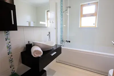 a white bathroom with a sink and a tub at House J São Rafael - By Bedzy in Albufeira