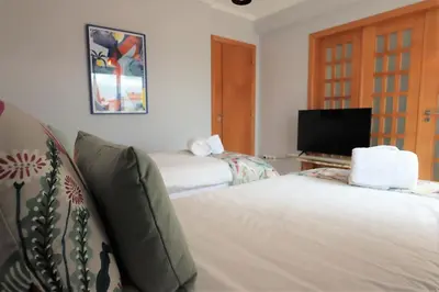 a bedroom with two beds and a flat screen tv at House J São Rafael - By Bedzy in Albufeira