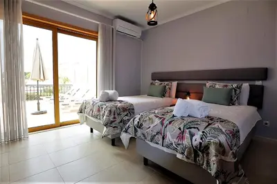 a bedroom with two beds and a large window at House J São Rafael - By Bedzy in Albufeira