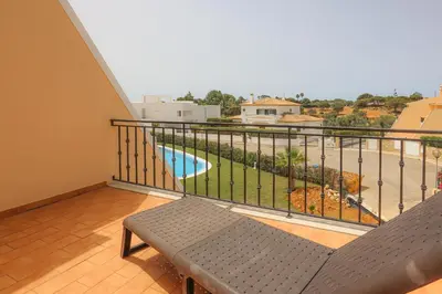 a balcony with a bench and a view of a pool at House J São Rafael - By Bedzy in Albufeira