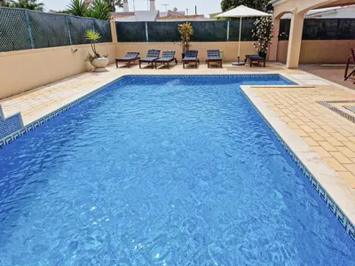 a swimming pool with blue water in a building at Qta do Eucalipto Villa in Faro
