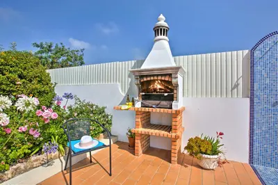 a outdoor oven with a table and a chair on a patio at Villa Goia by Villa Plus in Olhos de Água