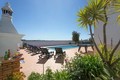 a lighthouse sitting next to a pool with chairs and a lighthouse at Villa Goia by Villa Plus in Olhos de Água